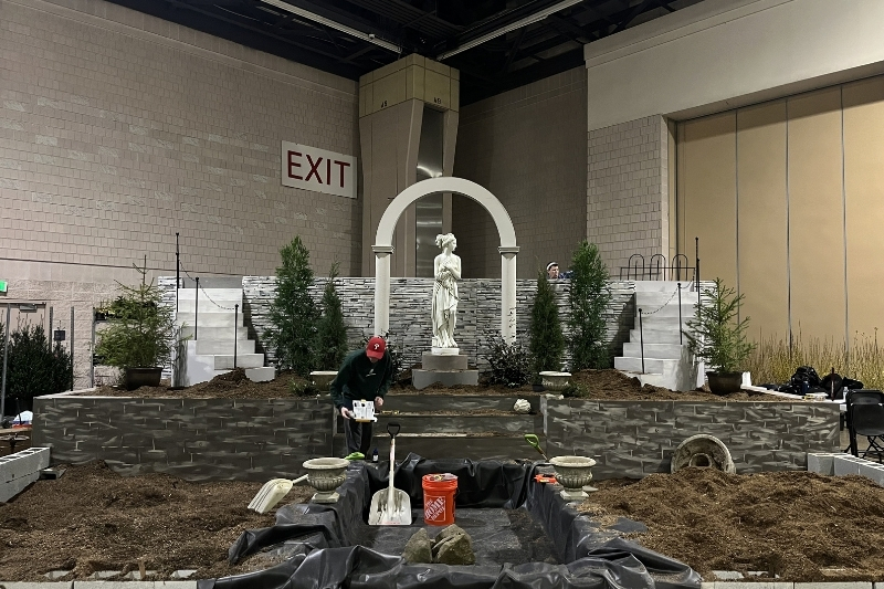 Students wrap up bringing soil into the exhibit. Stefanie Hansen in the back, behind the statue, installs the fence, and Joe Romano, in the front, looks at the pond dye. 