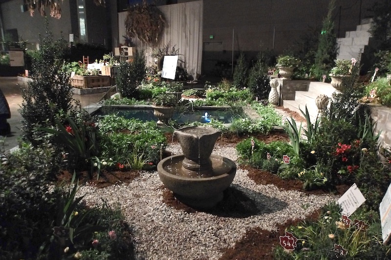 This is the warm-flowered side of the exhibit with the concrete fountain. Some of the plants included here are red flowering azaleas, the grassy and strappy foliage of the iris and the yellow dianthus flowers. 