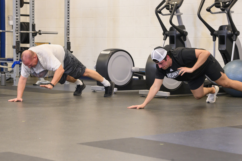 Veteran Andy Werner (left) and Andrew Low, a forward on UD’s ice hockey team, go push-up for push-up.
