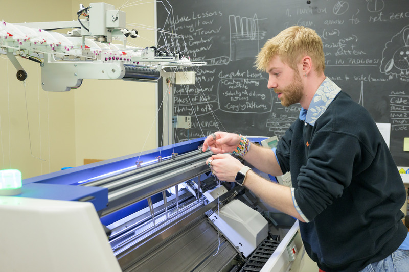 Tyler works with the yarn in UD’s Shima Seiki knitting machine, which was used to create the belly bind textile.