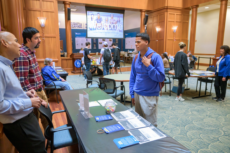 Student in blue shirt at Major/Minor Exploration Week speaks with UD staff and faculty