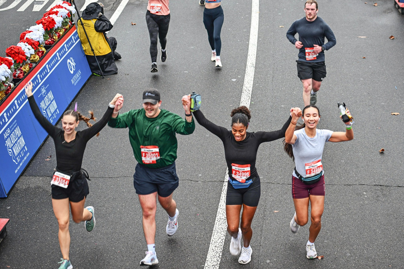 Four UDPT students run the Philadelphia Marathon. They are pictured with their race bibs and hands in the air