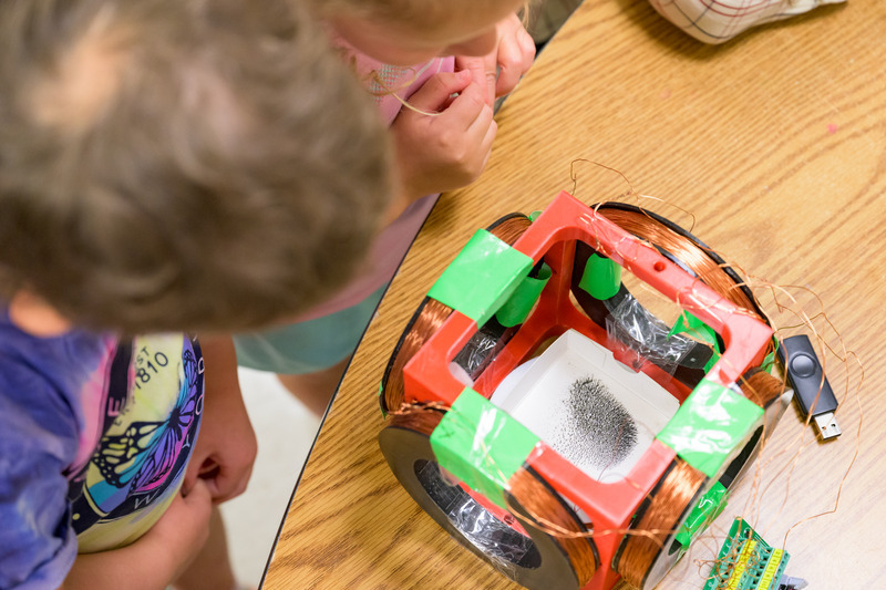 Students watch as iron filings respond to a magnetic field. The activity gave the children a chance to see magnetism in action, connecting an invisible force to something they could observe.