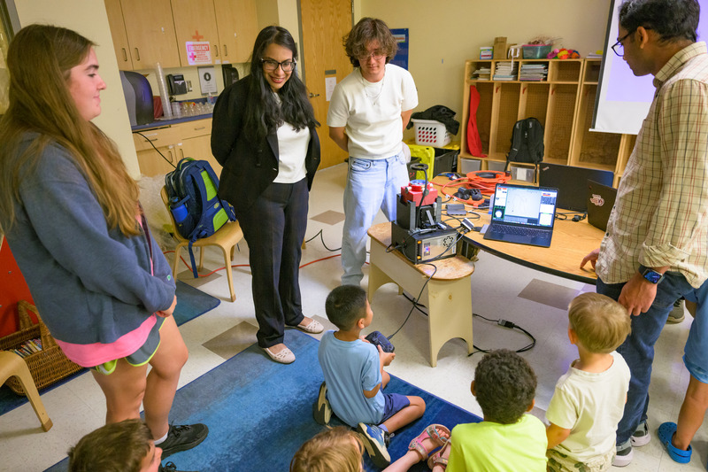 Das, Lee and Cherukumilli watch as a student takes his turn controlling the microrobots. Explaining their work to young children offered the researchers a fresh perspective on concepts they encounter every day in the laboratory.
