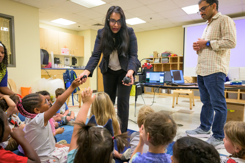 Das hands students 3D-printed shapes as Cherukumilli looks on. The researchers used the models to help children connect the design of a robot with how it moves and functions.