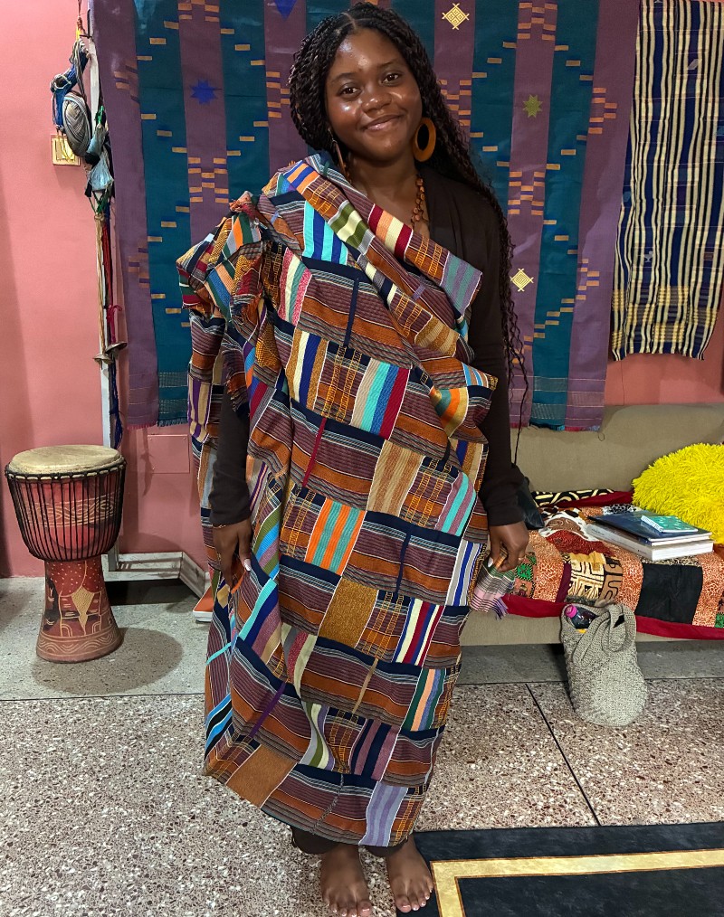 Brown wrapped in a Kente cloth. This piece was made from sewing several strips of the colorful and symbolic cloth together. 