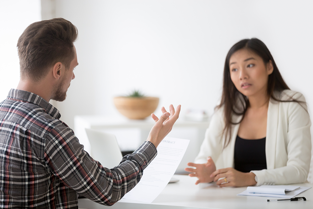 Two people having a discussion over paperwork. 