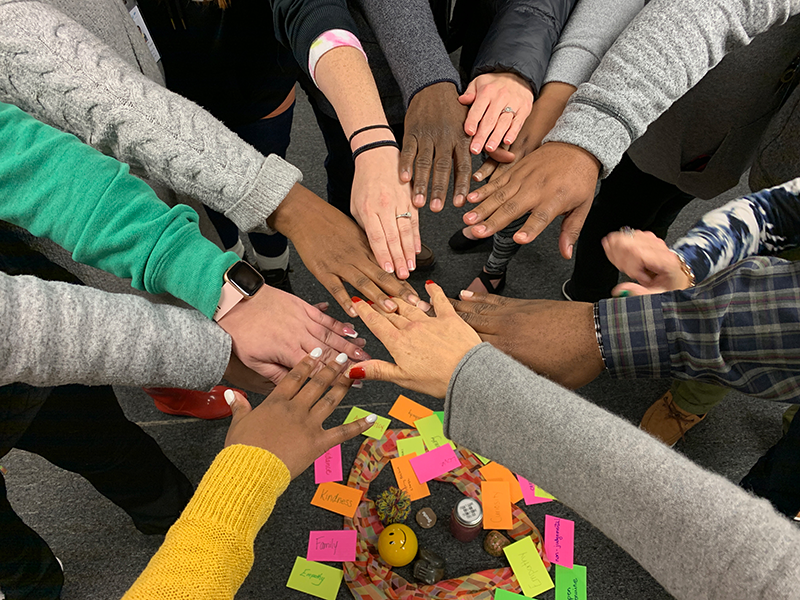 Group of adults and students put their hands in together