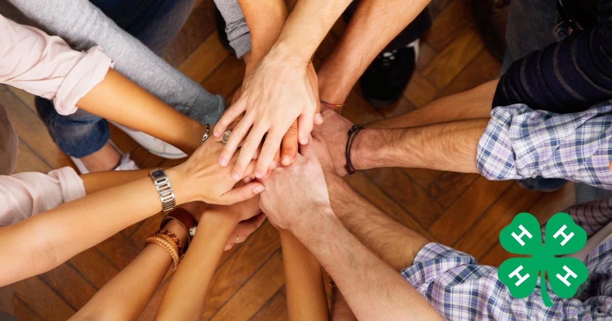 Ten adults, all hands in the middle with a 4-H logo