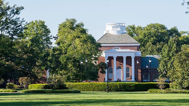Exterior shot of Memorial Hall steps and columns on a sunny day with a green tree in the foreground