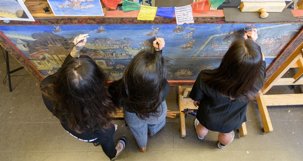 Three students working on restoring an old painting
