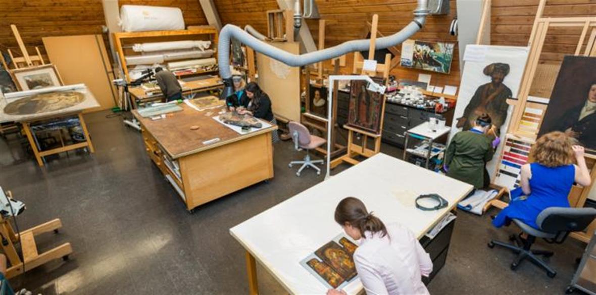 Art Conservation workshop with tables and a student looking over old artwork