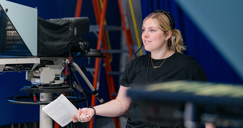 Nicole Travis, University of Delaware student and executive producer of STN49 News, stands in front of a camera inside the STN studio.