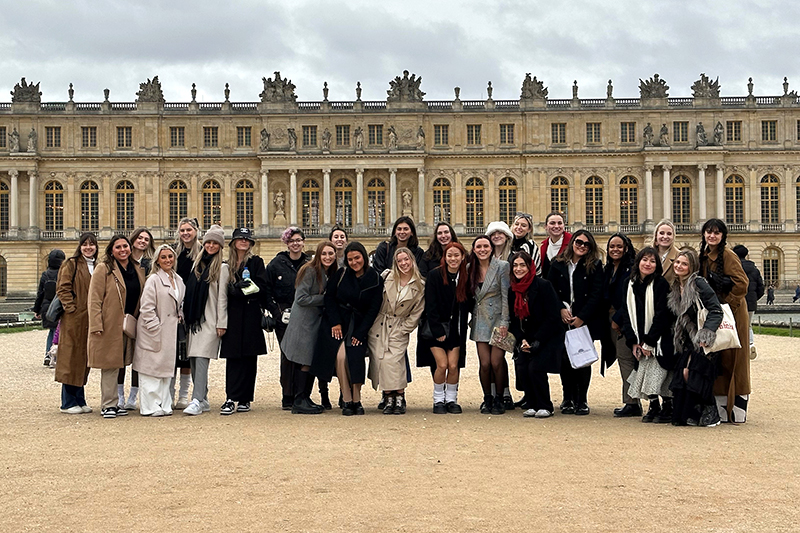 A group of 27 college students in front of the Palace of Versailles in Paris
