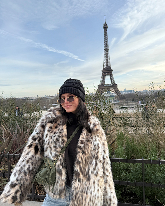 ​Student in fur coat in front of the Eiffel Tower in Paris, France