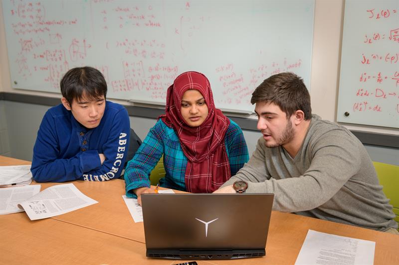 Graduate Students studying together at a table with a laptop