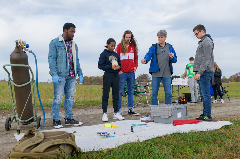 Diverse group of students with professor out in a field with a research balloon