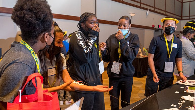 Neuroscience doctoral student Devashish (Dev) Pande puts an electrode on a middle school student's arm during a STEM outreach event at the University of Delaware.