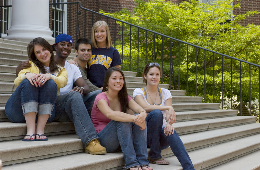 A group of six college students sit on the steps of Memorial Hall at the University of Delaware.