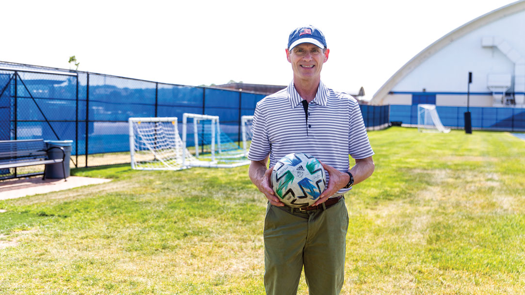 An image of a professor posing with a soccer ball