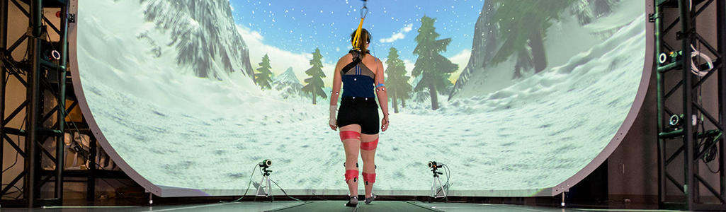 A woman connected to monitoring equipment is walking on a treadmill.