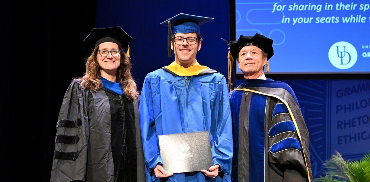 Water Science and Policy graduate poses with faculty at Interdisicplinary Convocation