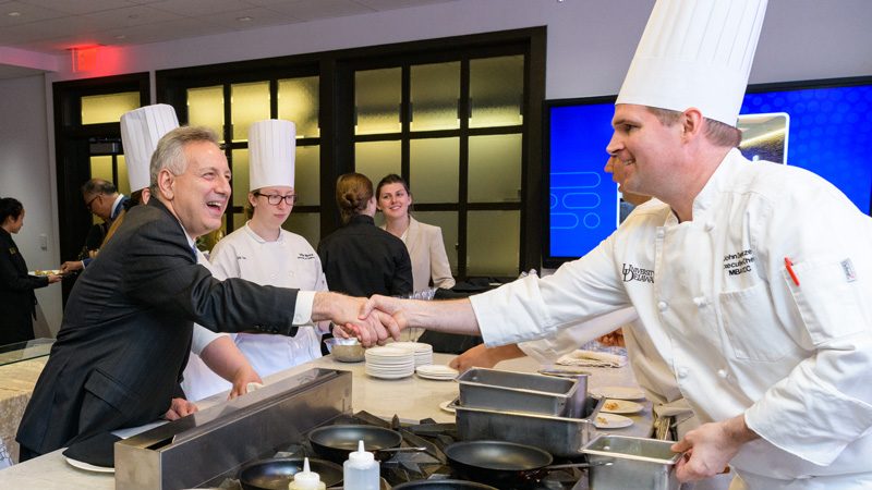 UD President Dennis Assanis (left) shakes hands with Executive Chef John Deflieze during the celebration of the Vita Nova renovation.