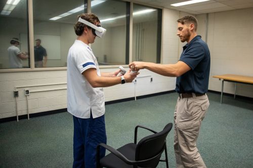 Nursing student wears VR headset and receives help from staff member