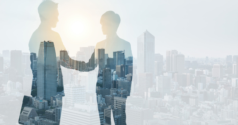 Silhouette of two people shaking hands superimposed over a city skyline