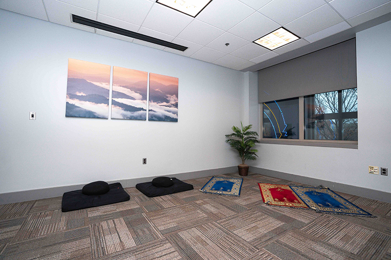 a quiet room with prayer mats on the floor and paintings on the wall