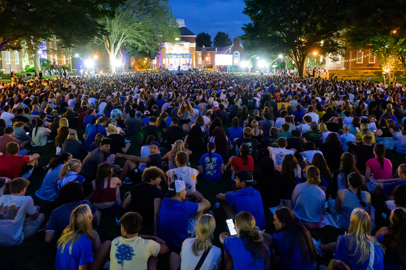 students gather on The Green with Memorial Hall lit up for the Twilight Induction Ceremony