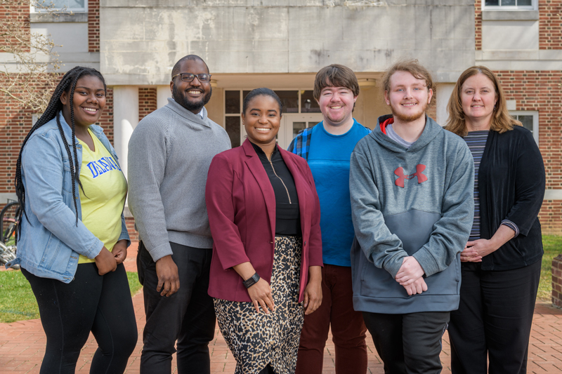 Group photo of past participants in the "Teachers of Tomorrow" program with program advisors and mentors. The program, developed by the College of Education and Human Development and funded through a UNIDEL grant, gives high school students a sense of what it's like to be a teacher education student.  Former Teachers of Tomorrow participants and current UD students: Anij'ya Wilson (denim jacket, yellow tee shirt); Cooper Middleton (blue plaid shirt w/ blue tee shirt); Michael Sensenig (grey Under Armour pullover)  Teachers of Tomorrow Staff: Imani Powell (grey shawl neck sweater), academic advisor for the Office of the Dean in the College of Education and Human Development and program manager for Teachers of Tomorrow; Deandra Taylor (red jacket), a doctoral student in the College of Education and Human Development and program coordinator for Teachers of Tomorrow; Kristine Ritz, senior assistant dean for student students in the Office of the Dean in the College of Education and Human Development and program director of Teachers of Tomorrow.