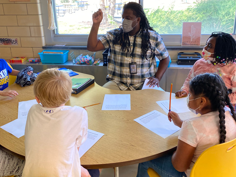 Titus Mims, a reading paraprofessional at Central Elementary School, engages in a Bookworms lesson with students.
