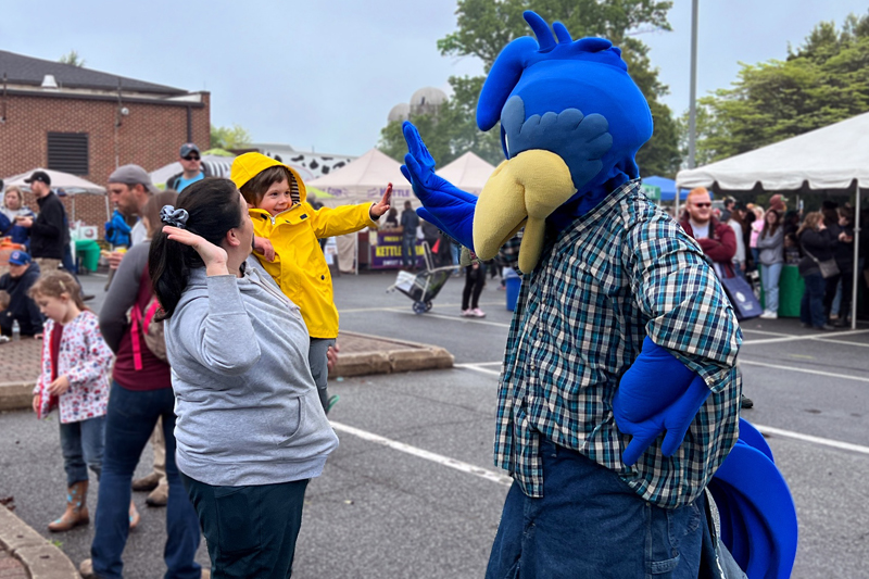 A child high-fives UD’s mascot YoUDee.