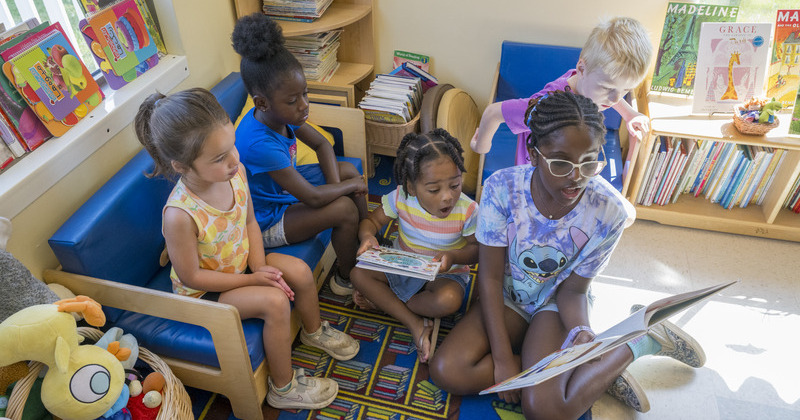 A young guest reader enjoys books with preschoolers at the Early Learning Center. 