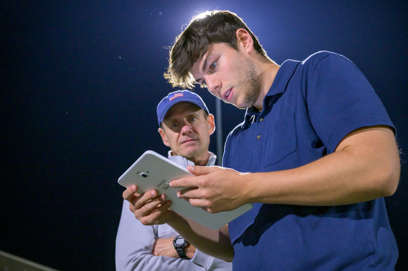 Thomas Kaminski, professor of kinesiology and applied physiology (left), and junior exercise science major Jonah Richmond (right) capture footage of a Delaware Football Club practice to validate any hits picked up by the sensors in players’ mouthpieces made by Wake Forest Medical Center and fitted by a local dentist and UD alumna Dr. Erin Macko.  