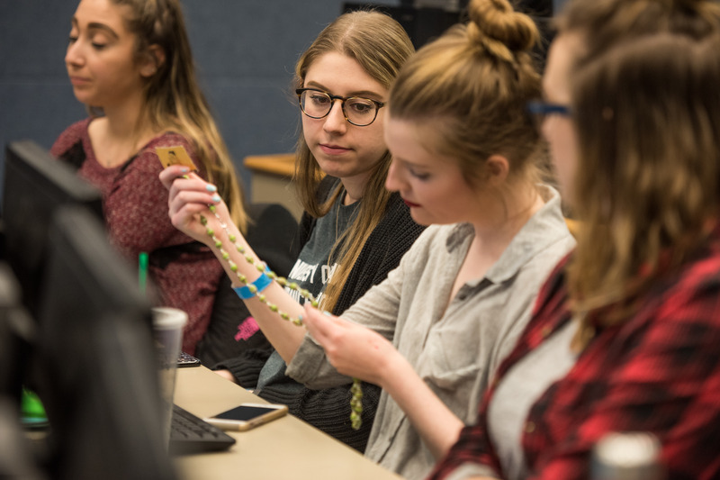 Fashion and merchandising students inspect samples of handmade jewelry from the Masai women of Kenya, for whom students will help develop marketing plans for their businesses.