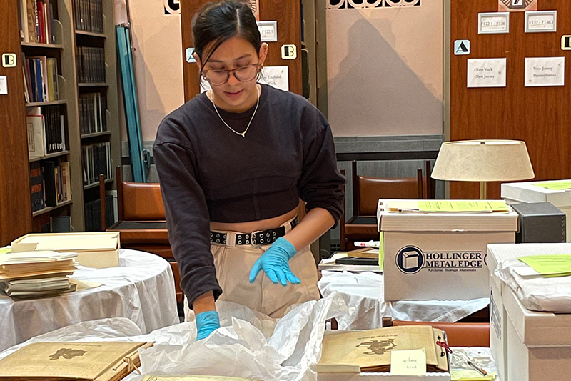 Akimah Kumar with a collection of scrapbooks that belonged to Delawarean Gloria Read.