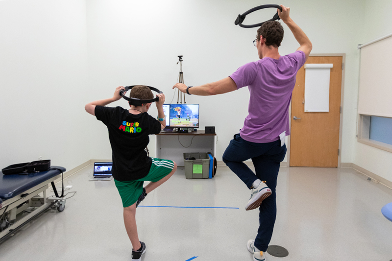 Reed, a 10-year-old boy with autism, gets his daily dose of exercise playing Ring Fit for Nintendo in Professor Physical Therapy Anjana Bhat’s Move 2 Learn Innovation Lab. Jacob Corey (right), a research assistant obtaining his doctorate in biomechanics and movement science, is working with Bhat on an exergaming study to determine whether Ring Fit can serve as an intervention that promotes motor skills, movement, and physical activity in individuals with autism, aged 7-21 years old.