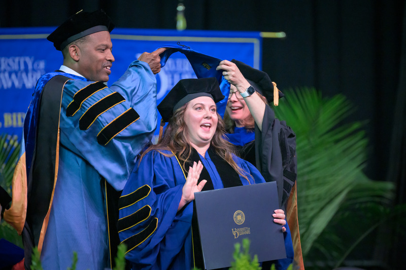 The hood that was draped over graduates’ shoulders is lined in Blue Hen blue and gold. The ceremony gives graduates the right to wear the hood along with a graduation gown with the three doctoral stripes on the sleeve.