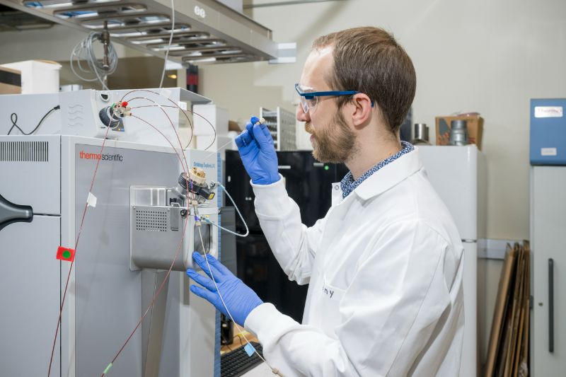 Tony Hollenback, a recent Ph.D. graduate, uses a precision needle to inject the phytate molecule purified from soil into the Orbitrap IRMS.