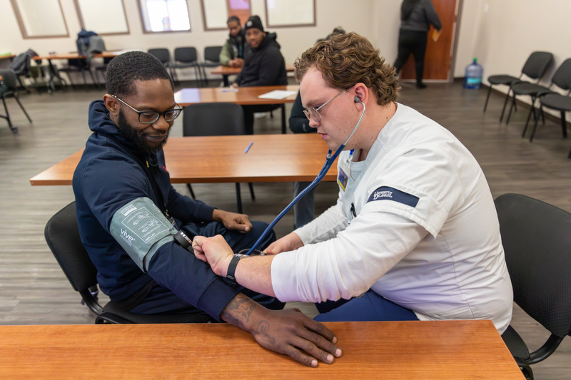 David Metcalf, a senior nursing major, checks a man's blood pressure during the Wilmington’s HOPE Commission’s Winner’s Circle, a weekly therapeutic peer support group for formerly incarcerated men and women.  