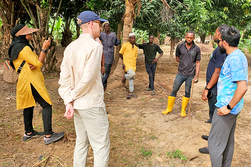 Kyle Davis (left) and Bhoktear Khan (right) talk to farmers in Nigeria about their farming practices. 