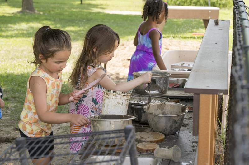 Preschoolers pretend to cook in the ELC’s outdoor mud kitchen. 
