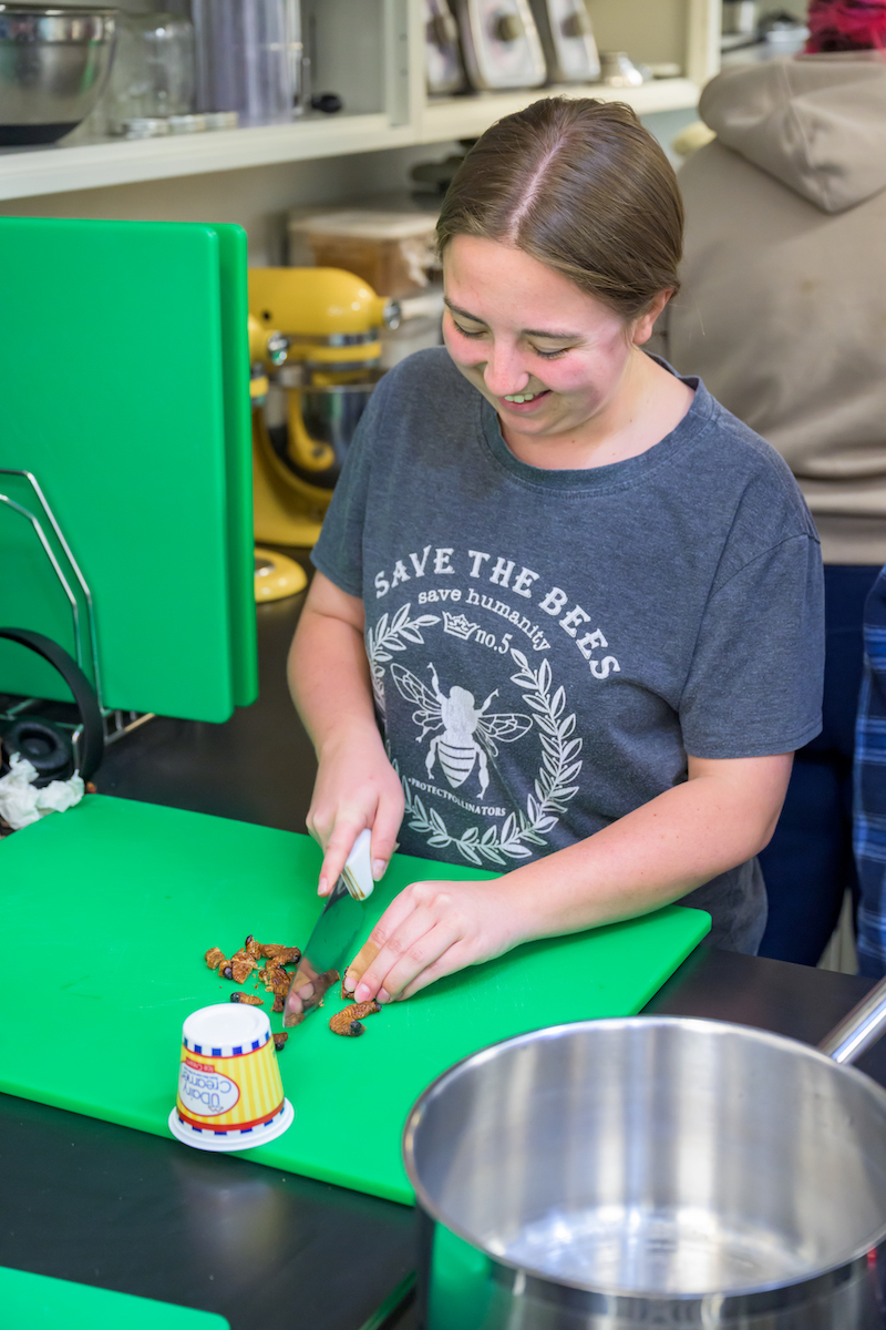 A student dices Sago worms to incorporate them into a black bean chili.
