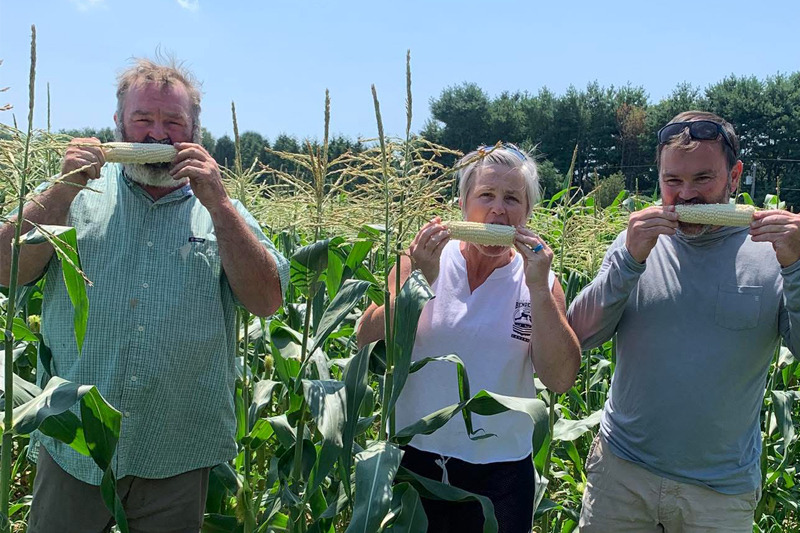 The Filasky siblings, John Filasky Jr., Julia Winkler and Tim Filasky, pose with John Jr.’s sweet corn, a customer favorite. John says his UD education helped him improve processes and better manage the farm.