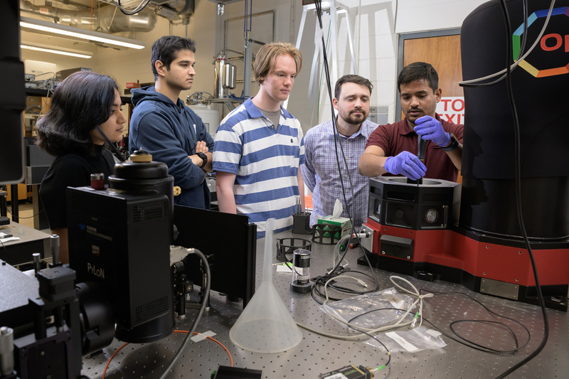 Chitraleema Chakraborty, Aqiq Ishraq, Alexander Hutchinson, Collin Maurtua and Muhammad Hassan Shaikh gather around a cryostat system used for low-temperature optical and electrical measurements in next-generation magnetic sensing research.