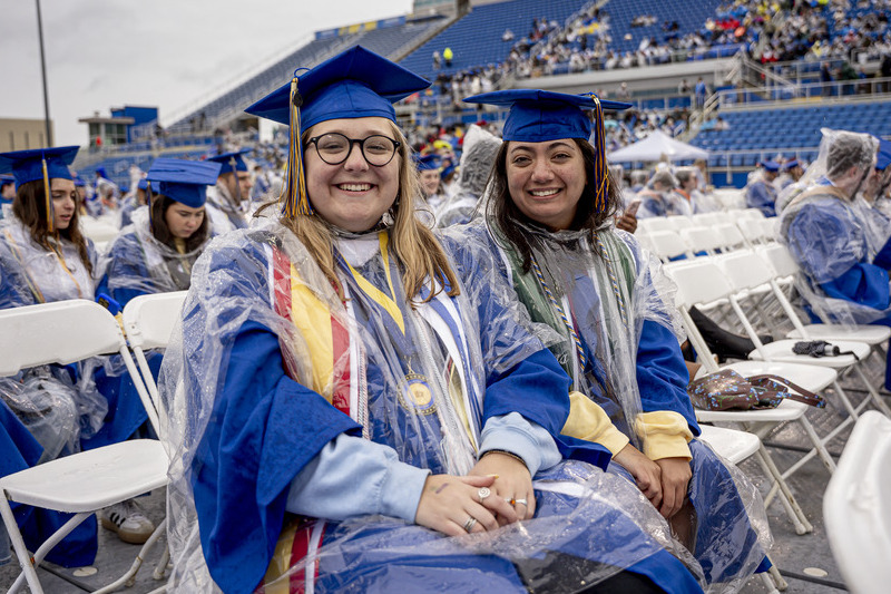 Graduates Annie McTaggart (left) and Erin Fitzgerald embraced the wind and rain at Commencement.